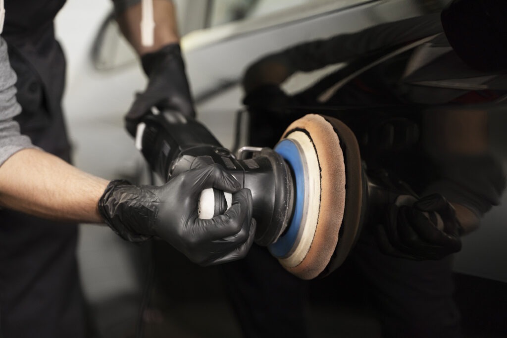 Technician using a machine polisher to restore car paint.
